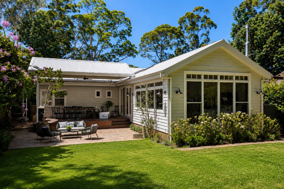 Renovated and extended weatherboard home in Turramurra by Armessen Build, with covered deck, paved terrace and garden